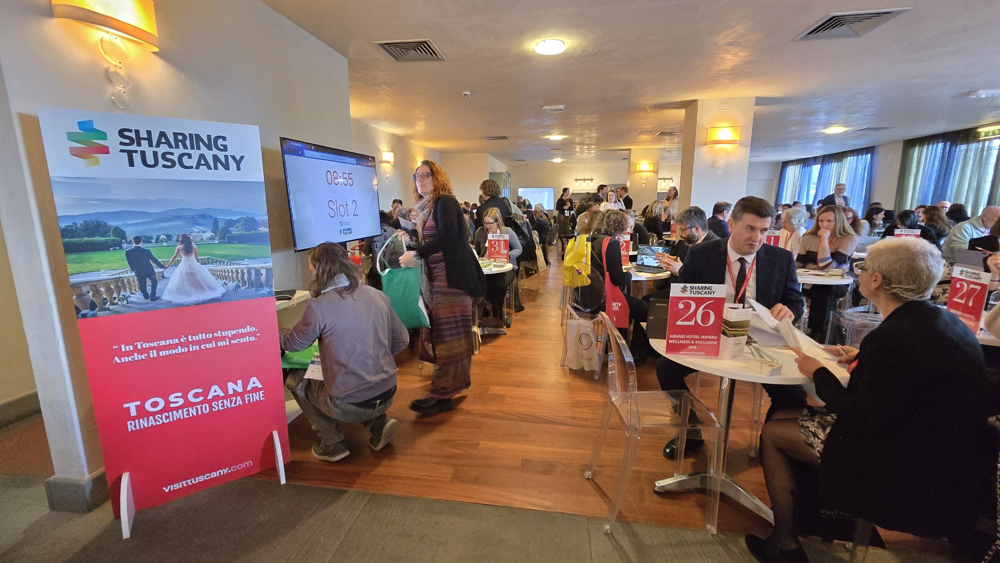 Immgine di persone sedute a tavolini tondi che si parlano